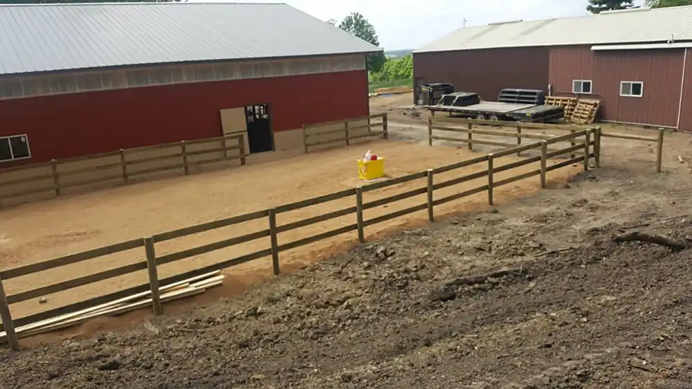 Timber paddock fencing and gates beside farm buildings